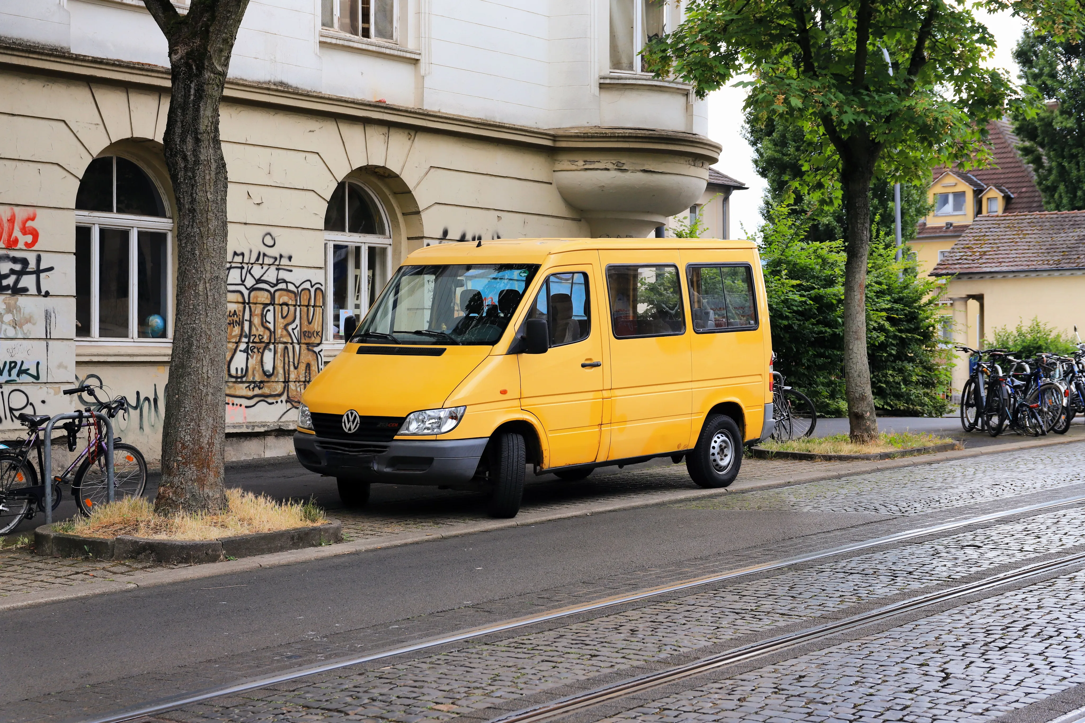 A yellow delivery van parked on a cobbled street
